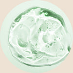 A close-up of a clear, slightly green gel with bubbles suspended inside, spread in a circular shape on a pale background.