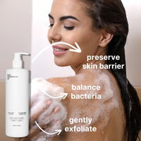 A smiling woman uses a foamy sponge on her shoulder in the shower. Text highlights Blemish-Free Body System by Basic Maintenance: preserves skin barrier, balances bacteria, and gently exfoliates. A large pump bottle appears in the foreground.