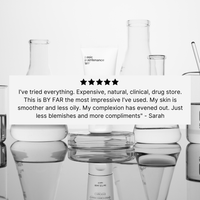 A white tube of The Face Lotion by Basic Maintenance sits among glass beakers and flasks. A five-star review overlay praises it for delivering smoother skin, fewer blemishes, and more compliments.