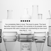 A white Basic Maintenance The Hand Soap dispenser and clear beakers sit on a white surface. A five-star review says, “I’ve completely fallen in love. The scent is great. The hand feel after using it is perfect… -A.S.”.